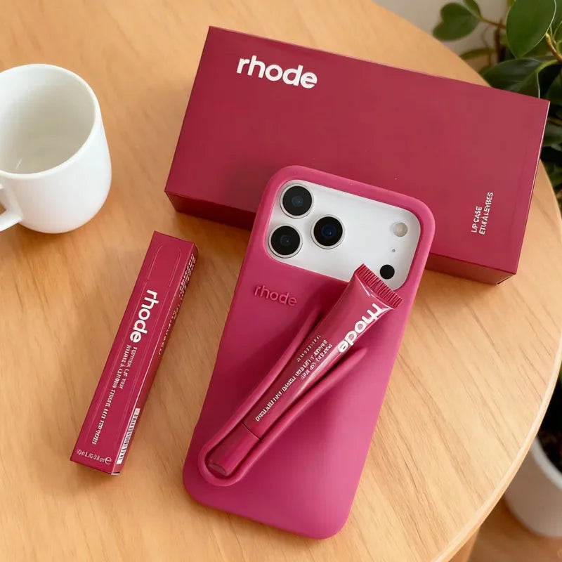 Pink phone case with matching pen and box on a wooden surface, featuring the 'rhode' brand.
