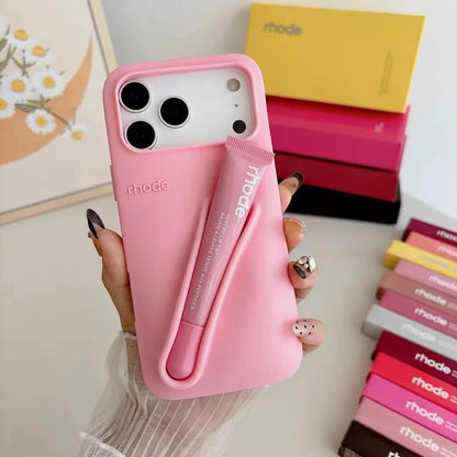 Pink Rhode phone case with 'rhode' branding held by a hand, with more phone cases in the background.