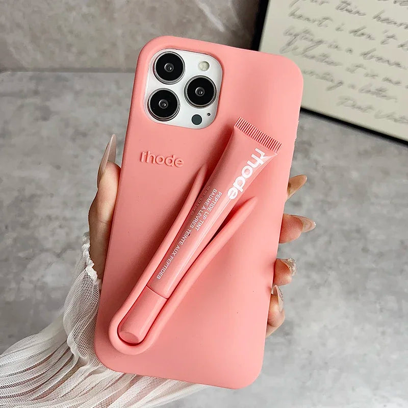 Pink phone case with a lip holder attached, held by a hand on a neutral background.