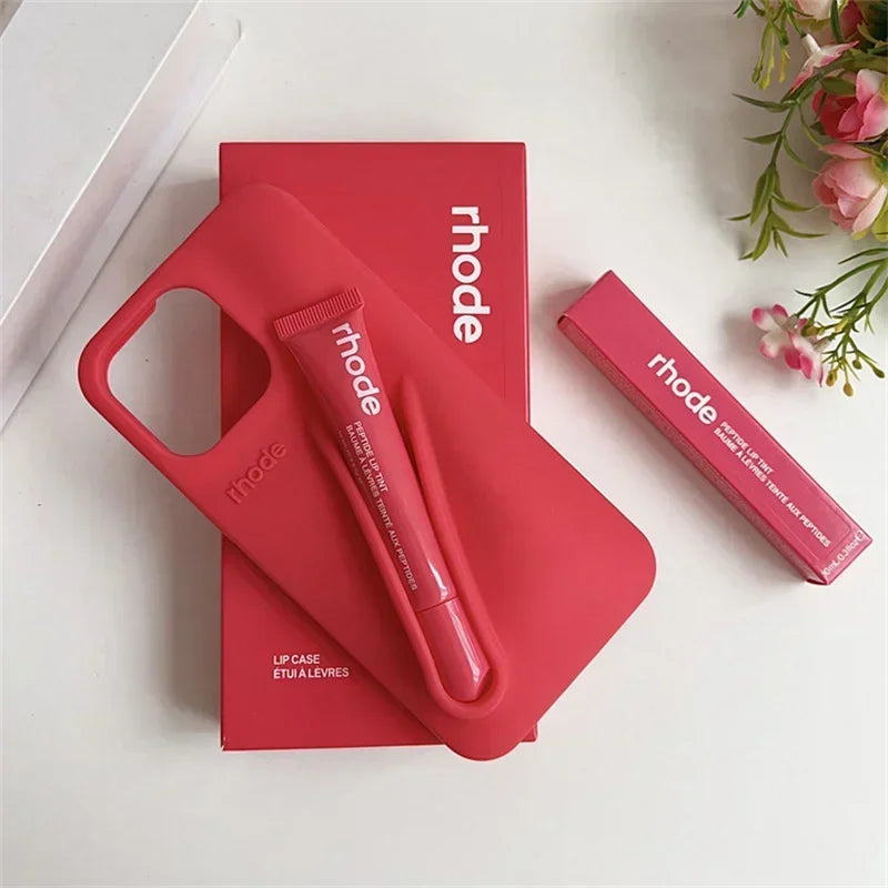 Red Rhode lip case and lip balm with 'rhode' branding on a white surface with flowers.