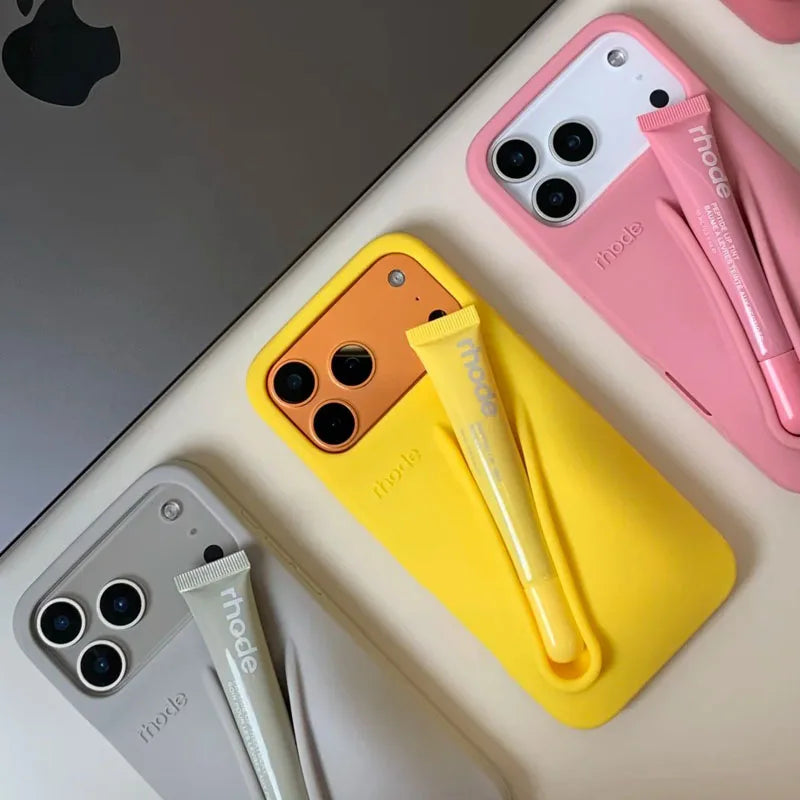 Three smartphones with colorful cases and accessories on a light surface