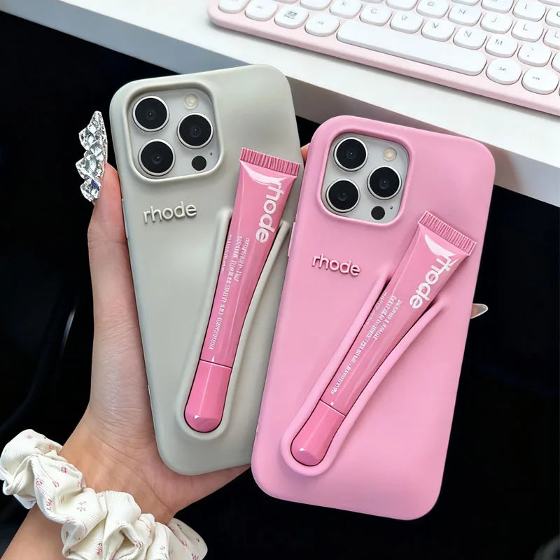 Two phone cases with a pen holder attached, one gray and one pink, held by a hand.