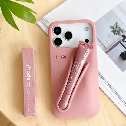 Pink Rhode phone case with pen and Rhode branding on a wooden surface