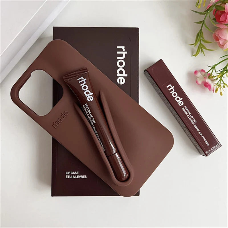 Brown lip case with lip balm and lipstick on a white surface with 'rhode' branding.
