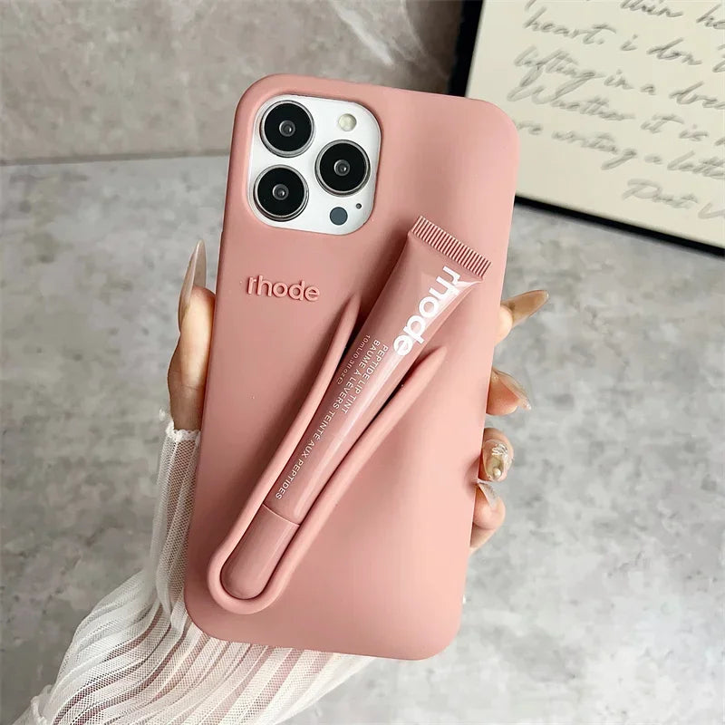 Pink Rhode phone case with a pen holder attached, held by a hand on a neutral background.